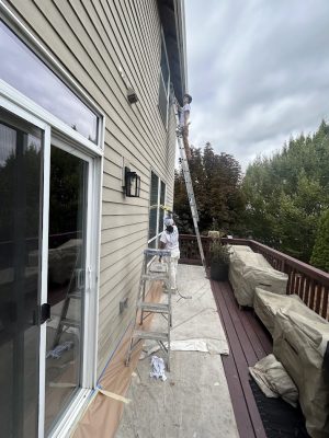Two painters work on a house exterior in Portland; one on a ladder, one by a window. Pearl Painters, Montoya project.