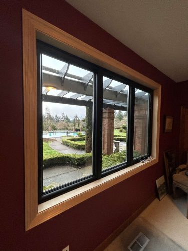 This McCormick interior in Portland features a large rectangular window with black trim, overlooking a landscaped yard. Pearl Painters is scheduled to complete painting by April 2025.