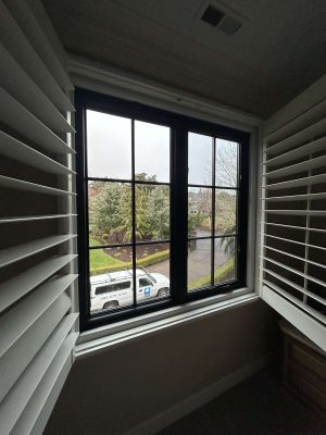 A Pearl Painters painting shows a window with black grid panes and open white shutters, looking out on trees, grass, and a white van—an April 2025 scene near Portland.