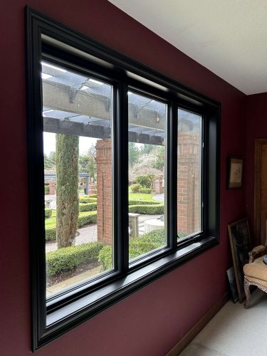 Portland painter Pearl Painters completed this McCormick-inspired interior in April 2025. The painting features dark red walls, a large black-trimmed window overlooking a garden, and a corner chair.