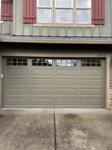 A Pearl Painters painter in Portland painted a two-story house with sage green siding, red shutters, and a light green Taylor garage door with rectangular windows (April 2025).
