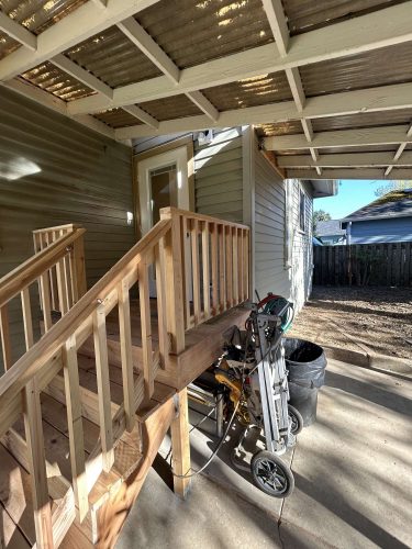 A painter’s equipment cart and trash can sit under the covered patio next to a wooden ramp at Congdon in Portland. Photo by Pearl Painters, April 2025.