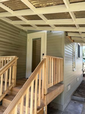 Painter Pearl Painters photographed the light gray Congdon house in Portland in April 2025, showing wooden steps with a handrail leading to a white door and covered porch.
