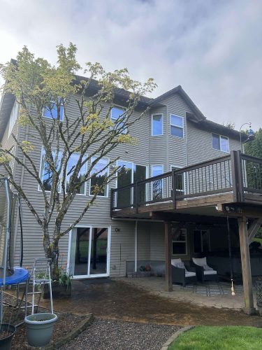Painter Scott showcases a three-story house in Portland with beige siding, large windows, and an elevated wooden deck. Pearl Painters completed the exterior painting, making it a standout property for April 2025 entertaining.