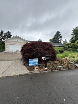 Single-story house in Cleveland, “For Sale” sign, bush by driveway, mailbox; cloudy July 2025. Painting not in Portland.
