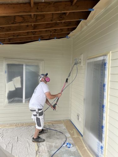 A painter from Mackey-Hinzdel uses a paint sprayer on an exterior wall, with windows and doors covered in plastic for protection—a common painting scene in Portland projects in June 2025.