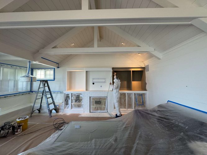 A painter from Pearl Painters is painting built-in shelves in a white interior with vaulted ceilings in Portland. Surfaces and floors are protected. Duffy project, May 2025.