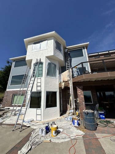 Pearl Painters is painting the exterior of the Anderson house in Portland in June 2025, with ladders, paint cans, and drop cloths in use. Windows and other areas are taped off for protection.