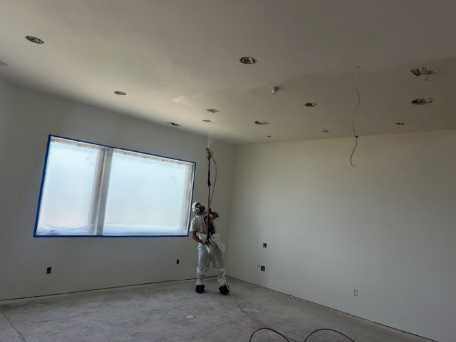 A painter from Pearl Painters is spray painting a white ceiling in an unfinished room in Portland as part of an interior project scheduled for completion by Wheeler in June 2025.