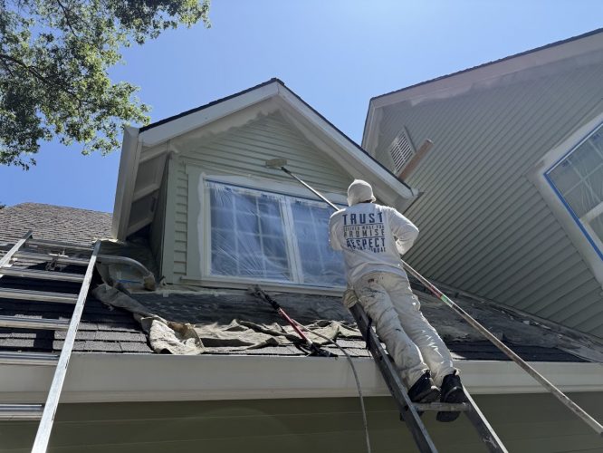 A painter with Pearl Painters paints the exterior of a Kearns house near a second-story window covered in plastic sheeting, June 2025.