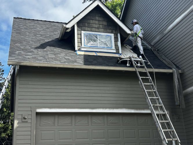 In May 2025 in Austin, a painter stands on a ladder painting exterior siding near a dormer window, with painting equipment on the roof. This work is not by Pearl Painters, who are based in Portland.