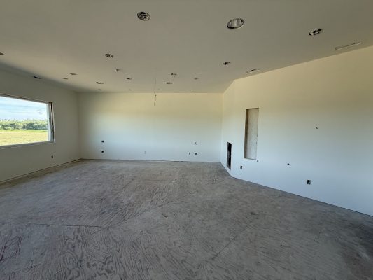 A large room at Wheeler in Portland is under construction, with unfinished floors, white walls, recessed ceiling lights, and one window. Pearl Painters expect to complete painting by June 2025.