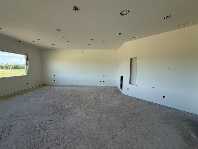 A large room at Wheeler in Portland is under construction, with unfinished floors, white walls, recessed ceiling lights, and one window. Pearl Painters expect to complete painting by June 2025.