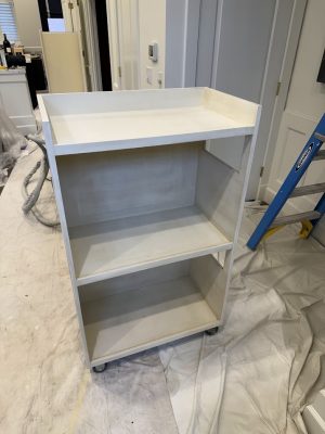 Unfinished white rolling cart on plastic sheet during painting; blue ladder and tools in background, likely Portland by Pearl Painters.