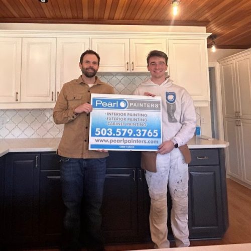Two men in a kitchen hold a Pearl Painters sign advertising painting services in Portland, with contact info.