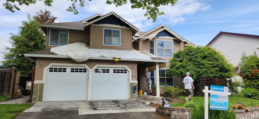 Two painters are painting a two-story house in Portland; tarp on garage roof. Yard sign: $3000 Pearl Painters discount.