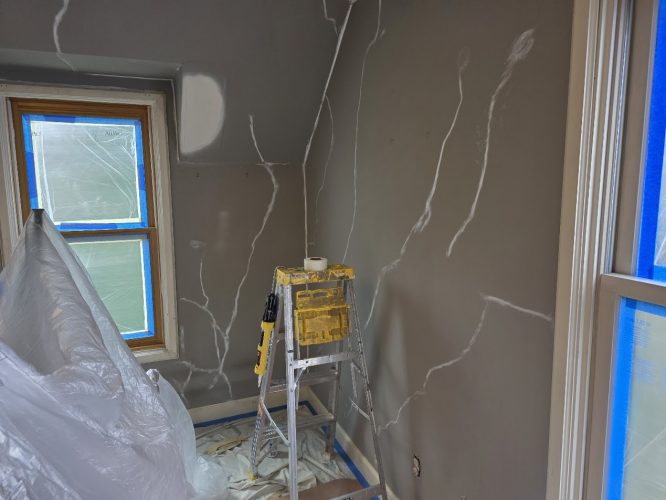 Room in Portland being prepped for painting by Pearl Painters: patched brown walls, ladder, tools, plastic sheeting, covered window.
