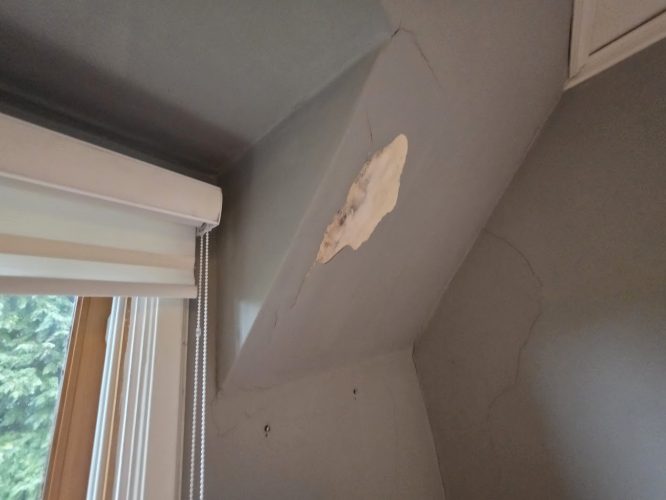 Damaged plaster with cracks on a sloped ceiling by a window and blind, ready for painting by Pearl Painters in Portland.
