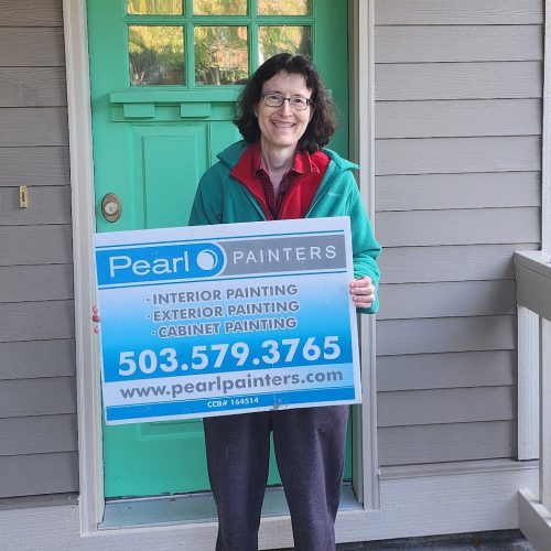 Woman on porch holds Pearl Painters sign for painting in Portland, listing services, phone number, and website.