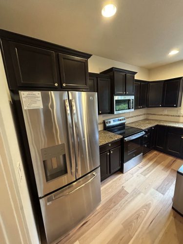 Kitchen in Rockaway Beach rental home with very dark kitchen cabinets before being painted