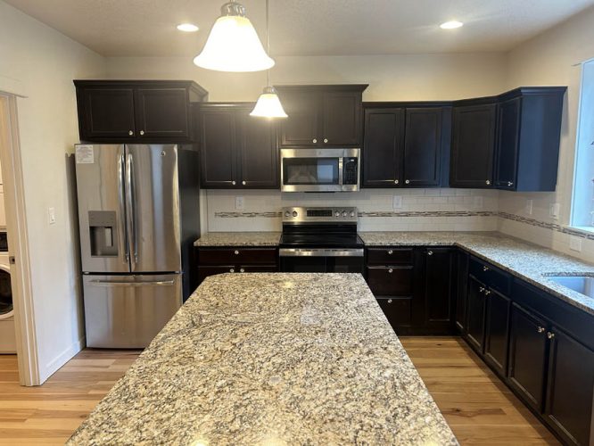Kitchen in Rockaway Beach rental home with very dark kitchen cabinets before being painted