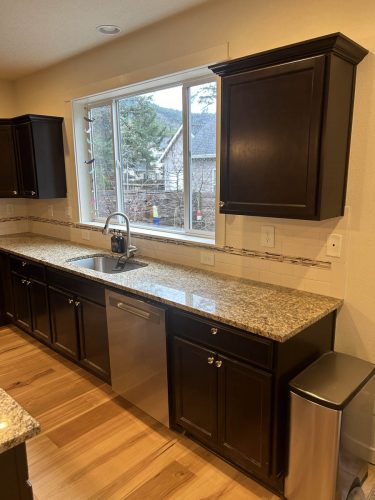 Kitchen in Rockaway Beach rental home with very dark kitchen cabinets before being painted