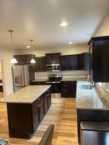Kitchen in Rockaway Beach rental home with very dark kitchen cabinets before being painted