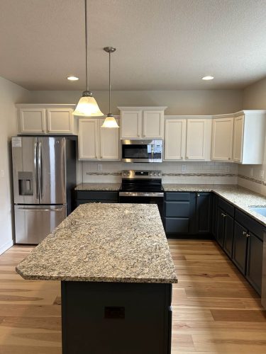 Kitchen in Rockaway Beach rental property, with white upper cabinets and dark grey blue lower cabinets, freshly painted