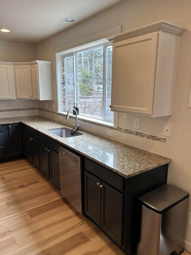 Kitchen in Rockaway Beach rental property, with white upper cabinets and dark grey blue lower cabinets, freshly painted