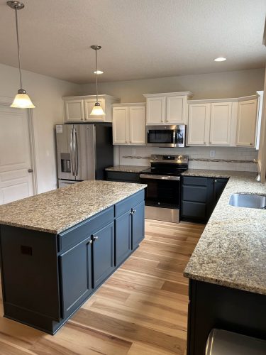 Kitchen in Rockaway Beach rental property, with white upper cabinets and dark grey blue lower cabinets, freshly painted