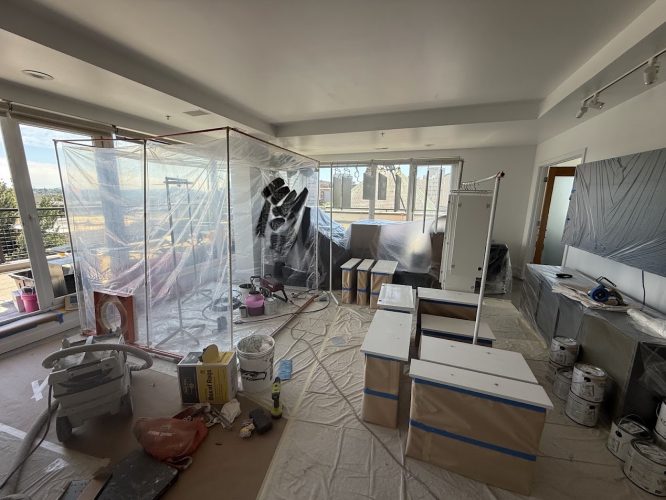 Pearl Painters cabinet painting in an apartment with plastic sheeting and equipment.
