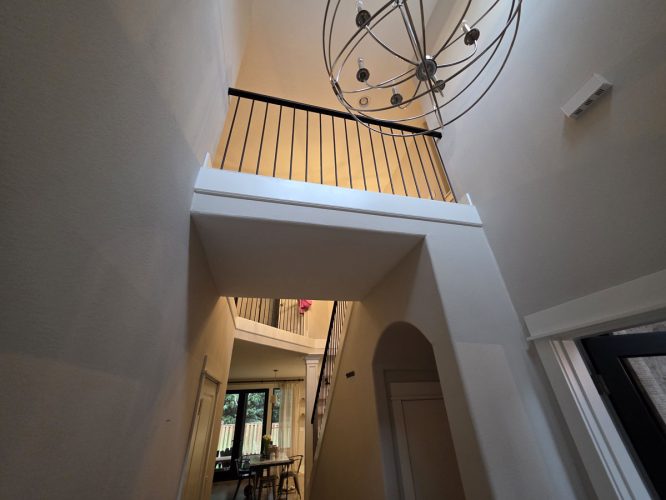 Modern Gilbo hallway in Portland with high ceilings, black railing, chandelier; dining area visible. Painted by Pearl Painters.
