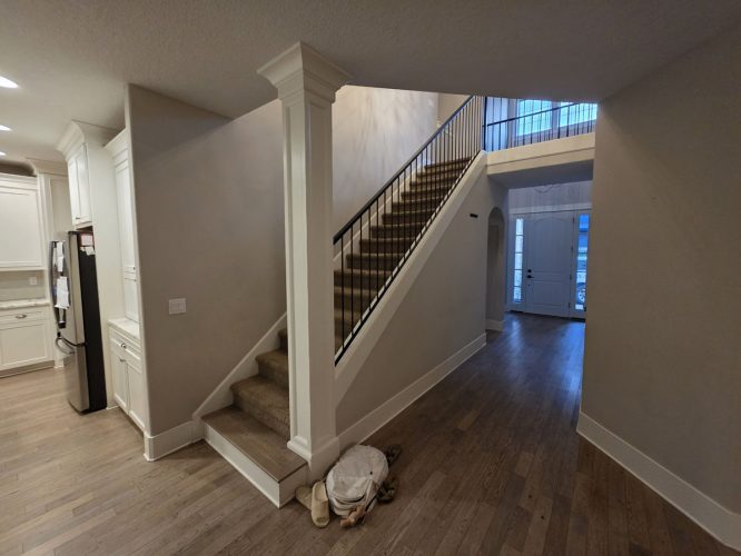 A Gilbo home in Portland with carpeted stairs, black railing, and wood floors. Painter’s bag and shoes by stairs; March 2026.