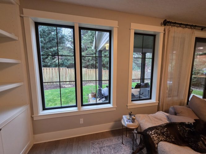 In Gilbo, large windows show a green yard; inside, a dog rests by a table and bookshelf. Painter or painting not shown.