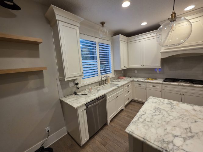 Bright kitchen with white cabinets, marble counters, and pendant lights in Portland, painted by Pearl Painters.