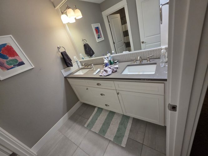 Portland bathroom with double sinks, gray counter, striped rug, Gilbo painting. Pearl Painters' work. March 2026.