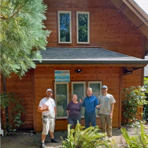 Four Pearl Painters team members stand in front of a wooden house with a company sign.