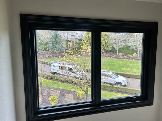 The view through the window shows Pearl Painters vehicles in West Linn. After photo of black trim freshly painted