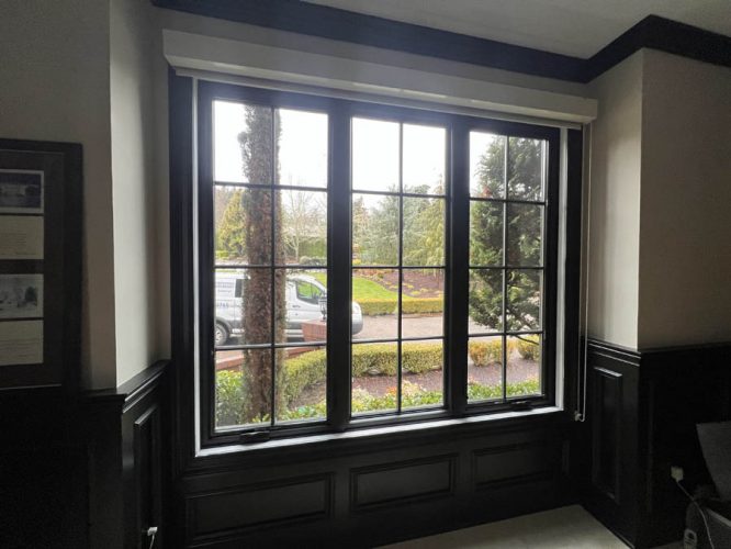 The McCormick residence in Portland has a large window overlooking a garden with trees and a parked van, surrounded by dark wood paneling.