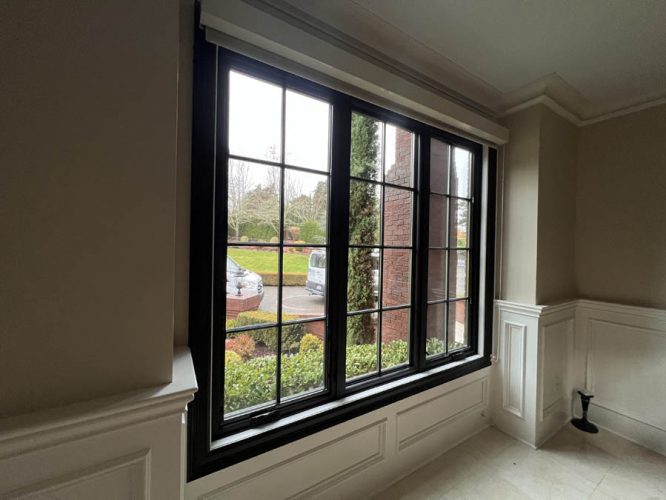 This West Linn interior features a large black-framed window, a driveway view with a van, and a landscaped garden.