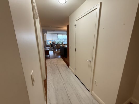 Cream walls painted by Pearl Painters in Portland; closed door right, white runner, living room with large windows ahead.