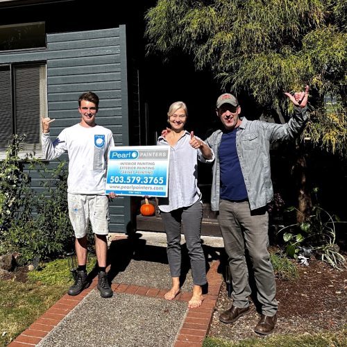 Three people with a Pearl Painters sign outside a house, pumpkin on porch. Likely in Portland. Sun is out. Painters smiling.