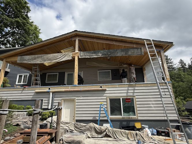 Painters on porch work on a house in Portland with ladders, tarps, and materials; job by Pearl Painters.