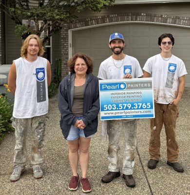 Three painters and a woman by a garage hold a Pearl Painters sign listing Portland painting services and contact info.