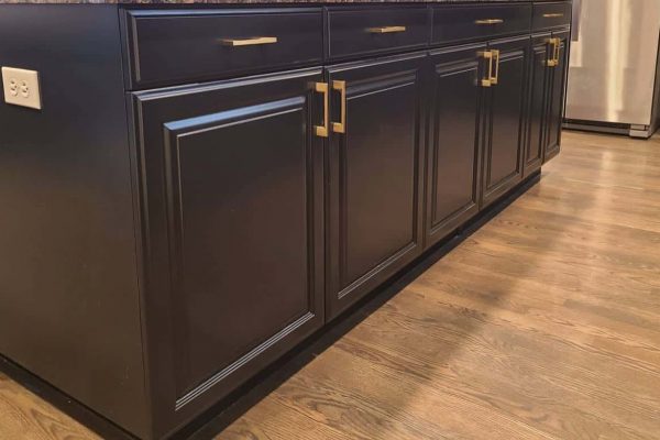 A modern kitchen cabinet makeover in Tigard featuring black cabinets and gold hardware.