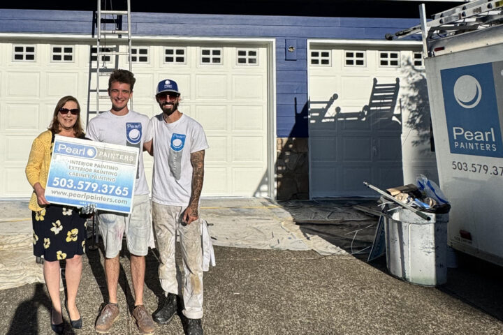 Three people hold a Pearl Painters sign in front of a blue house. Pearl Painters van, painting gear, and garage are visible—Portland.