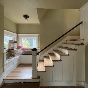 A stairway in a house with white walls and wood floors is transformed with the impact of handrail painting.