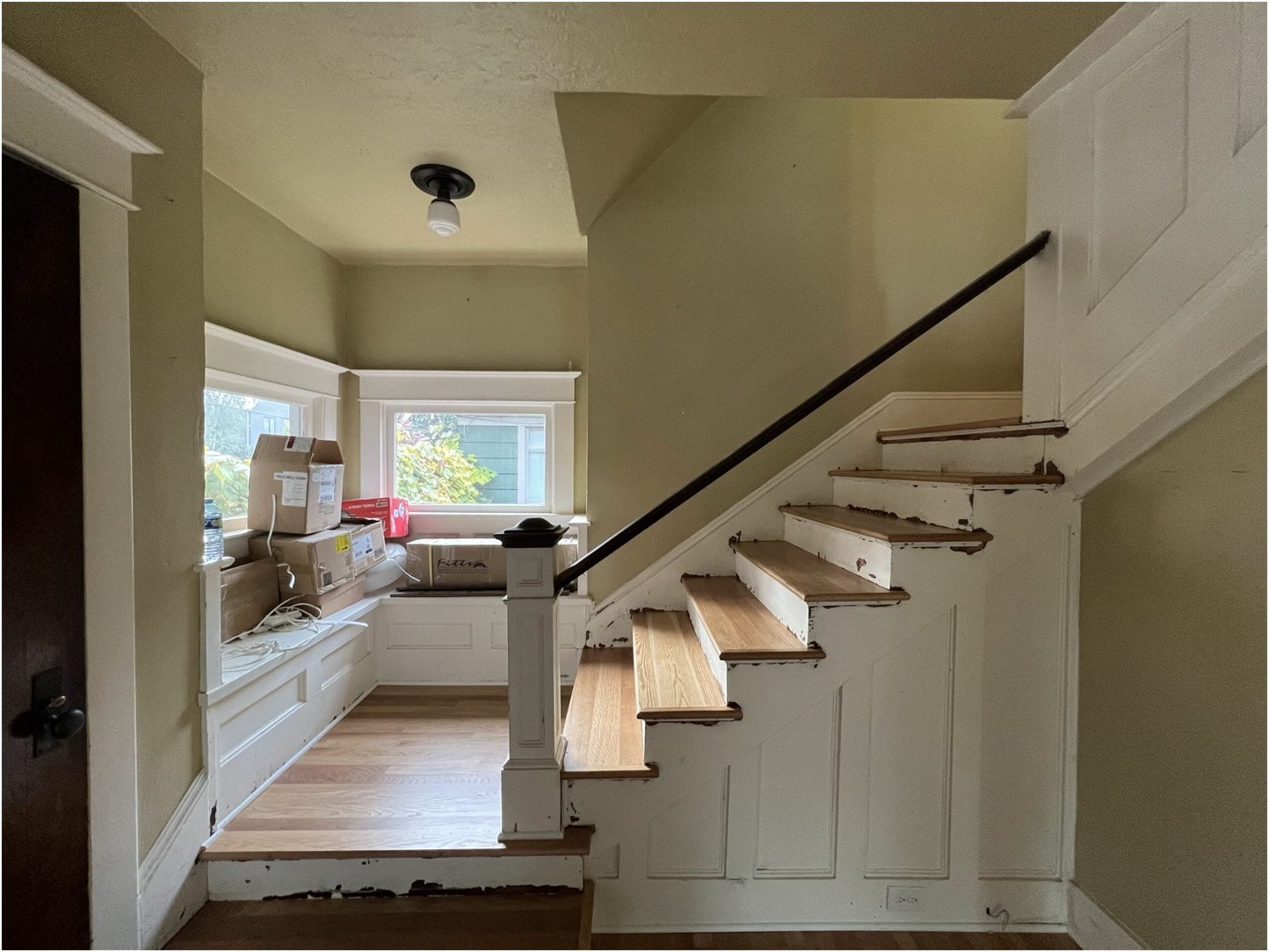 A stairway in a house with white walls and wood floors is transformed with the impact of handrail painting.