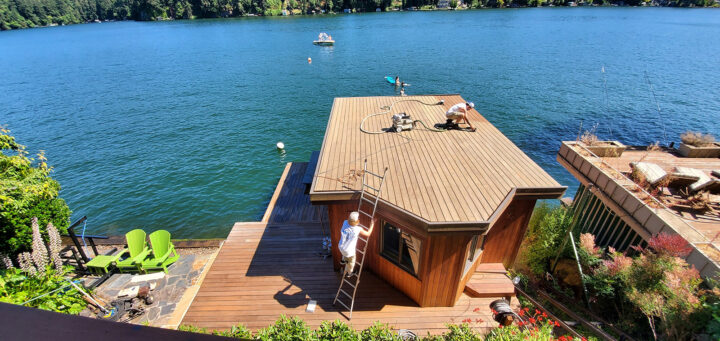 Two painters working on staining the roof of a houseboat in Oregon