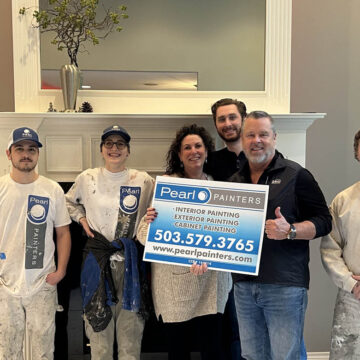 Group of painters posing with a company sign after completing an interior painting project in Tigard.